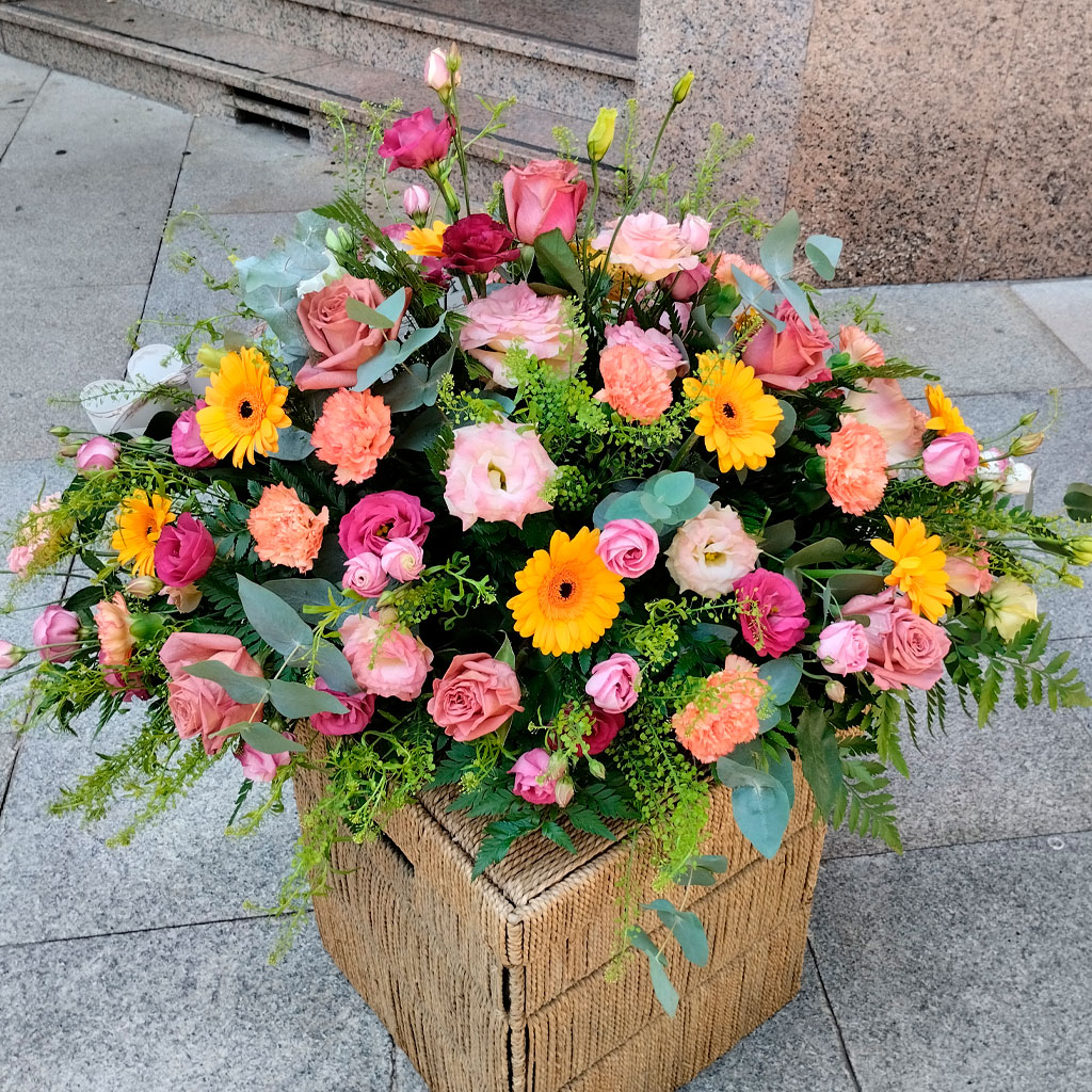 ramo de gran tamaño dentro de una cesta de fibras naturales, con flores de colores amarillos y diferentes tonos de color rosa